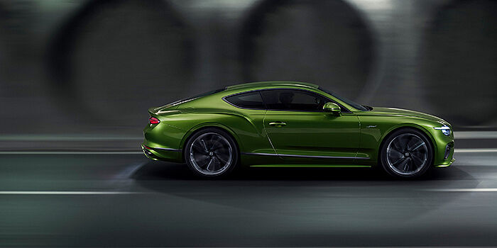  Bentley Belfast Bentley Continental GT coupe in Tourmaline Green paint driving in profile on a dark road