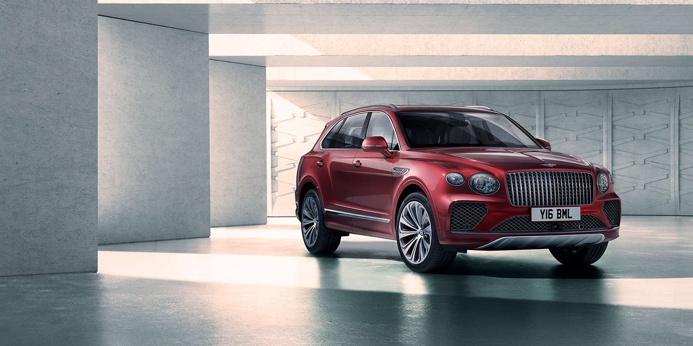 Bentley Belfast Bentley Bentayga Atelier Edition SUV in Rubino Red paint front three quarter against textured concrete wall