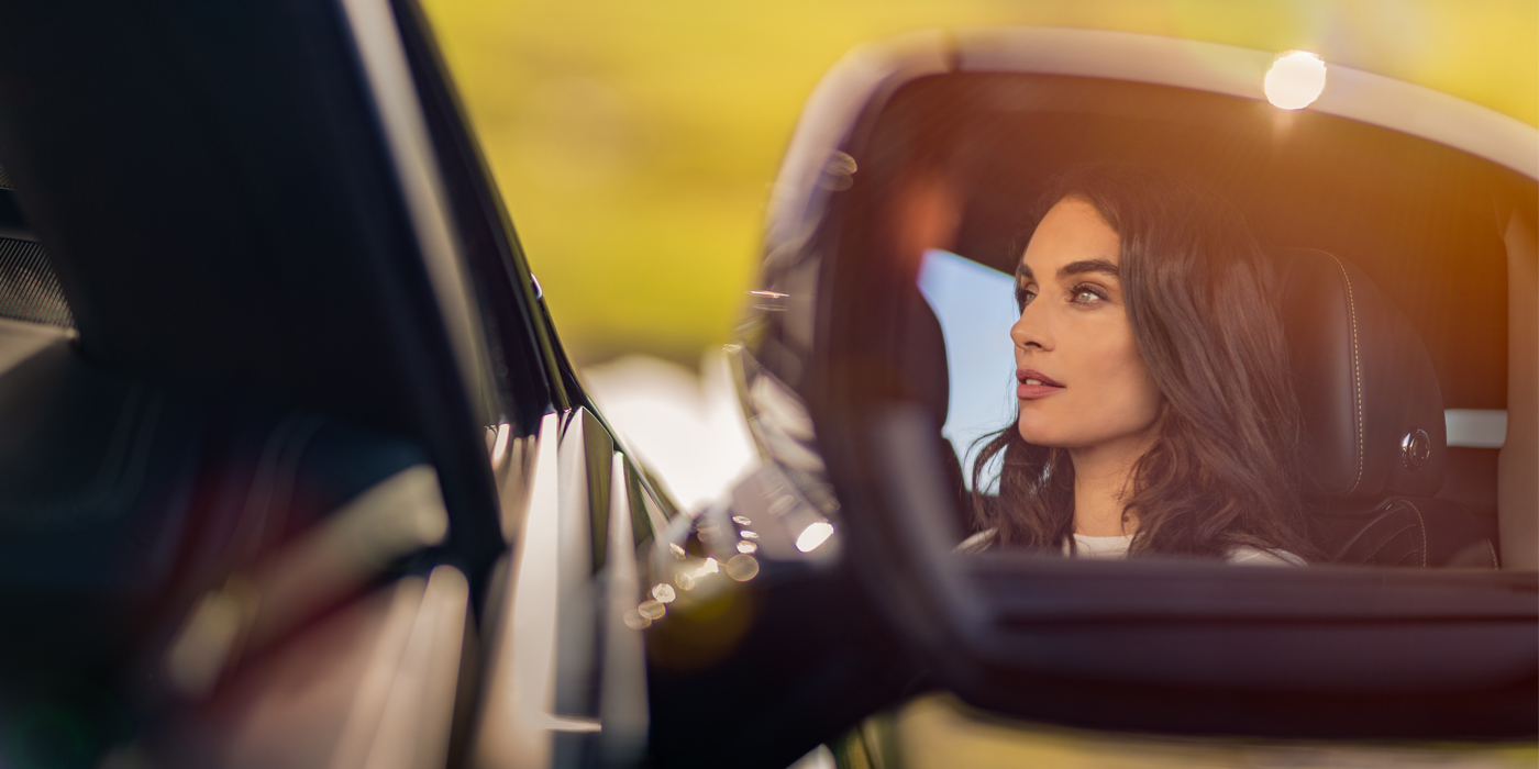 Bentley Belfast profile of dark haired woman's face in mirror of Bentley car in sunlight