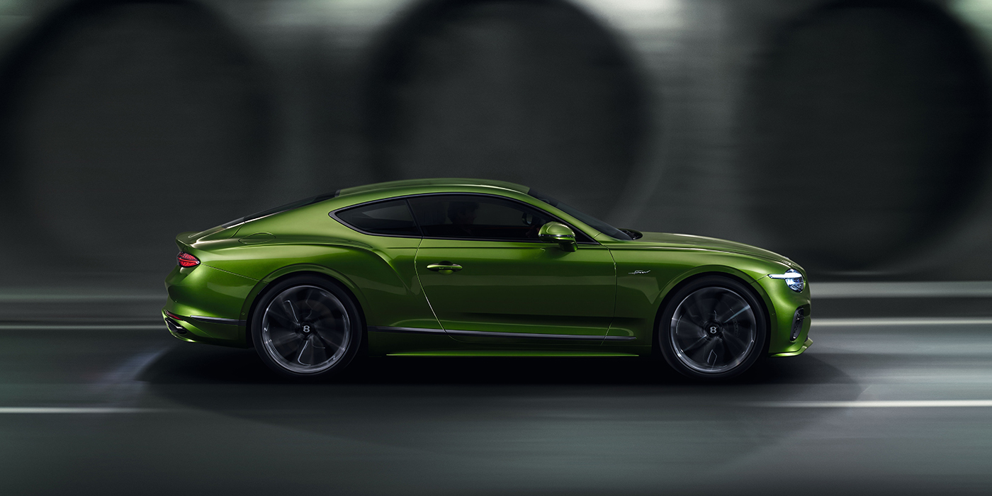 Bentley Belfast Bentley Continental GT coupe in Tourmaline Green paint driving in profile on a dark road